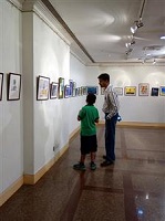 Father and son discuss a painting on display at Khula Aasmaan - Children's Art Exhibition - Edition I, presented by Indiaart Gallery	